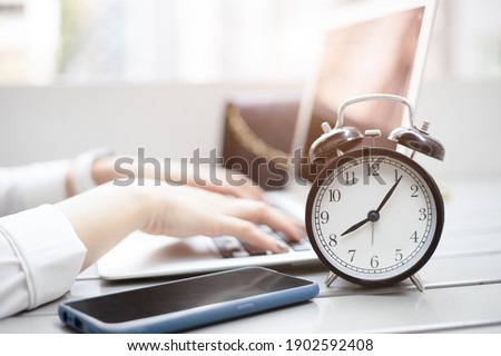 Business working times concept people work typing on laptop computer overlay with in time clock in the morning