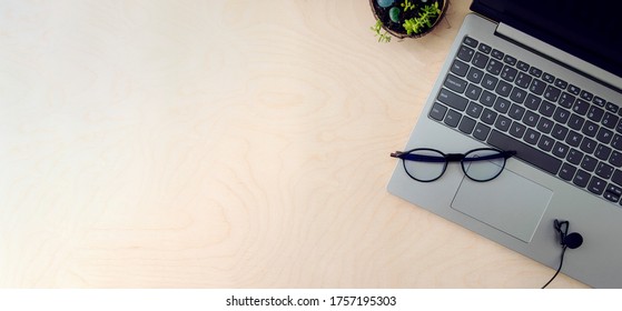 
Business Workspace. Online Education Concept. E-learning. Online Training. Laptop, Microphone And Glasses For The Computer On A Wooden Background, Top View, Copy Space,banner