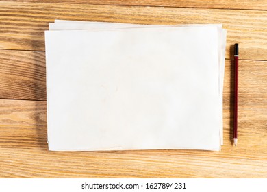 Business Workspace With Sheet Of Paper And Pencil Lying On Wood Table. View From Above With Copy Space. Rectangular Blank White Paper Stack On Textured Natural Wooden Background. Business Presentation