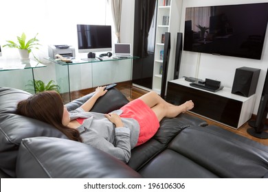 Business Young Woman Watching TV In Modern Home Office With Computer And Laptop