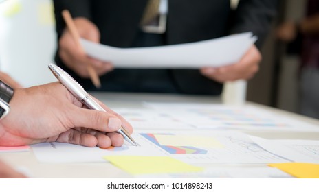 Businessmale hand pointing at business document during discussion at meeting,Their colleagues discussing data on desk table,Close up business team analysis and strategy concept,Business teamwork,