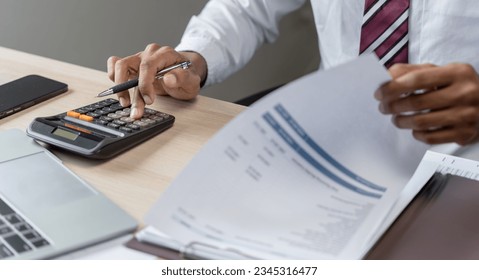 Businessman Accountant analyzing investment charts Invoice and pressing calculator buttons over documents. Accounting Bookkeeper Clerk Bank Advisor And Auditor Concept.