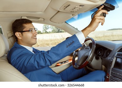 Businessman adjusting the rearview mirror while driving a car