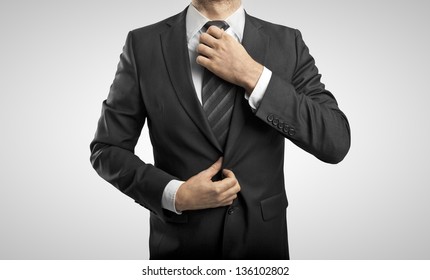 businessman adjusts tie on gray background - Powered by Shutterstock