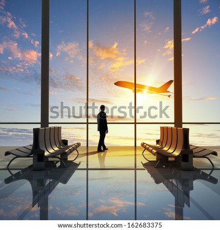 Businessman at airport looking at airplane taking off