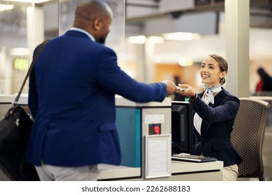 Businessman, airport and passenger assistant helping traveler with checkin at terminal counter. Black male with passport and service agent in travel help, security or immigration for airline control - Shutterstock ID 2262688183
