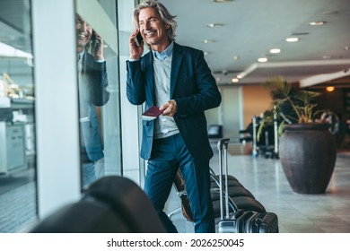 Businessman At Airport Waiting Lounge And Talking On Cellphone. Male Traveler At Airport Lounge Using Mobile Phone.