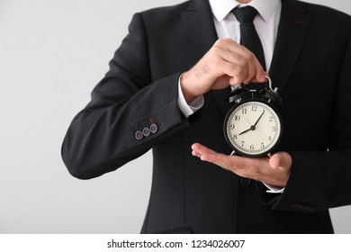 Businessman with alarm clock on light background, closeup - Shutterstock ID 1234026007