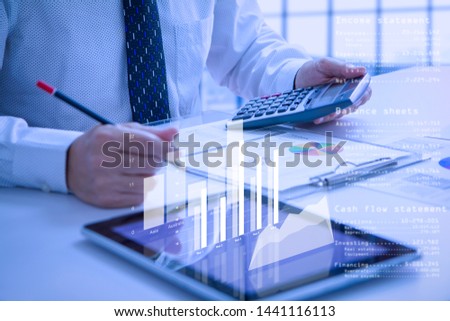 Businessman or analyst holding calculator while reviewing financial statements for business performance or cash flow analysis