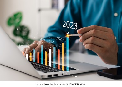 Businessman analyzes profitability of working companies with digital augmented reality graphics, positive indicators in 2023, businessman calculates financial data for long-term investments. - Shutterstock ID 2116009706