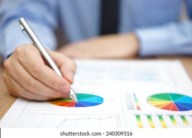 Businessman is analyzing business report with charts and diagrams