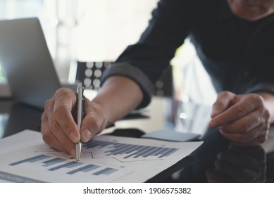 Businessman analyzing business report and planning work project on paper notepad with financial graph report document, spreadsheet and laptop computer on table in modern office, close up - Shutterstock ID 1906575382