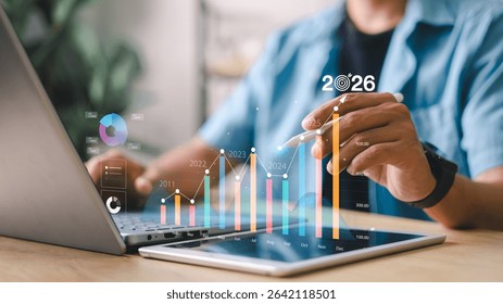 Businessman analyzing digital data graph with yearly growth trends and bar charts. Concept of financial forecast, KPI dashboard, and business performance analytics.