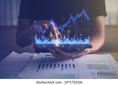 Businessman analyzing financial, fund, account data from growing investments. Virtual graph reporting using digital technology. Man touching tablet at working room. Business finance growth concept. - Powered by Shutterstock - Get 15% off with code: PIKWIZARD15