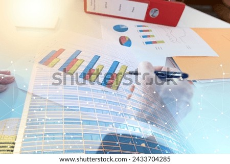 Businessman analyzing graphs at office; multiple exposure