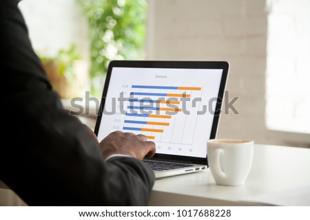 Businessman analyzing monthly stats graph on laptop screen, making annual project financial report data analysis using computer software applications for business statistics concept, close up view