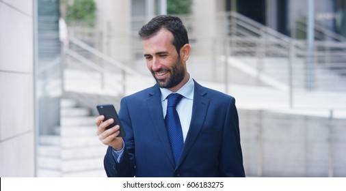 A businessman answering the phone, send messages and smiles for the beautiful job news and in the background you see a people. Concept: technology, telephony, business trips, business, wall street