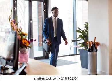 Businessman Arriving For Work At Office Walking Through Door