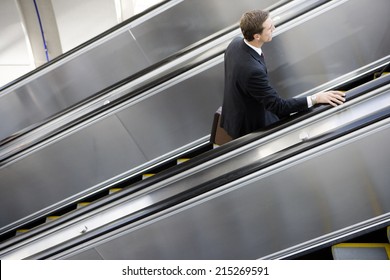 Businessman Ascending Escalator, Side View, Elevated View