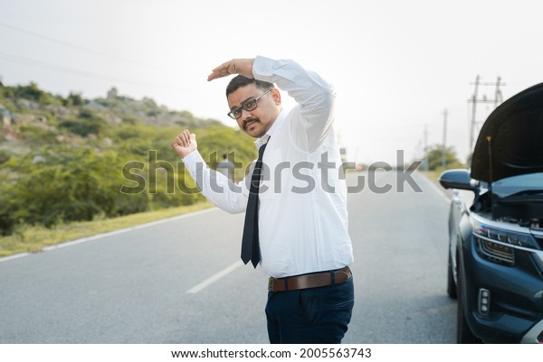 Businessman\
asking for lift or hitchhiking due to car breakdown while traveling\
- concept of asking help while\
commuting