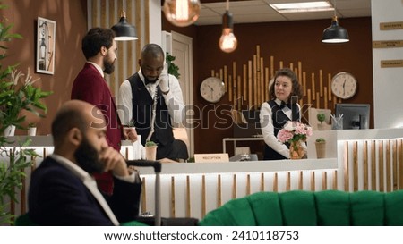 Businessman asks for front desk services, talking to hotel concierge personnel about facilities while he travels for work. Entrepreneur in suit arriving at reception for check in process.