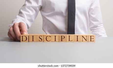 Businessman Assembling A Discipline Sign With Wooden Blocks.