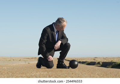 Businessman attached to a ball & chain. - Shutterstock ID 254496553