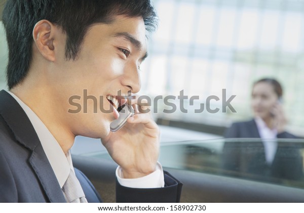 Businessman in back seat\
of car on the phone