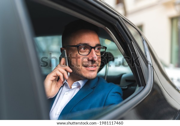 Businessman in\
the Back Seat of a Taxi Having Phone Call. Spanish Business Man\
Using Phone in the Car. Business\
Concept.