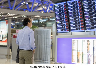 Businessman With Backpack In Airport Look At Flight Timetable.
