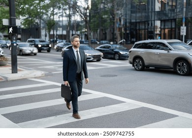 Businessman with backpack walking in city. Side view of male entrepreneur in classy suit and with takeaway drink walking along crosswalk while commuting to work in morning. businessman in the street - Powered by Shutterstock