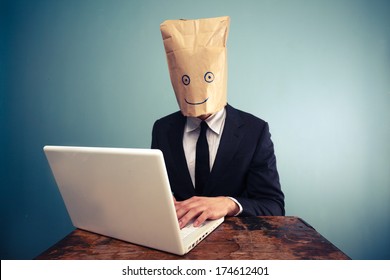 Businessman with bag over head working on computer