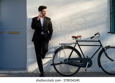 Geschäftsmann mit Fahrrad hört Telefon an der Wand