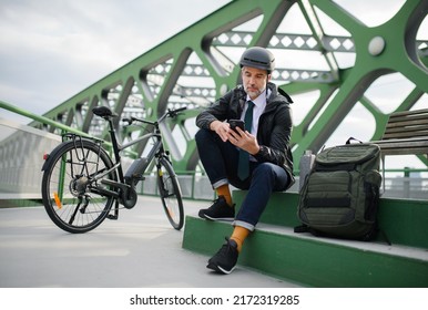 Businessman with bike sitting on bench, using smartphone. Commuting and alternative transport concept - Powered by Shutterstock