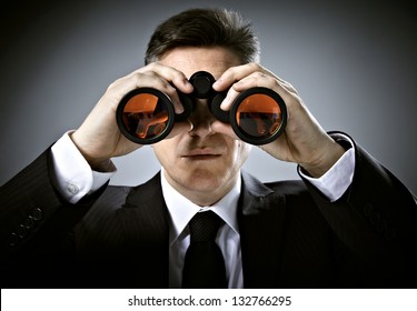Businessman with binoculars. Over gray background.
