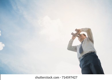 Businessman with binoculars spying on blue sky. Businessman Hand Holding / looking / watching using Binoculars. - Powered by Shutterstock