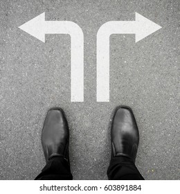 Businessman In Black Leather Shoes Standing At The Crossroad Making Decision Which Way To Go - Two Ways To Choose.