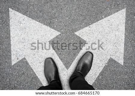 Businessman in black shoes standing at the crossroad making decision which way to go. Decision making concept.