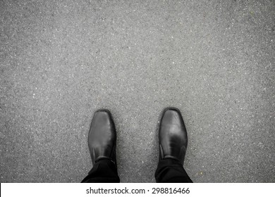 Businessman in black shoes standing on the asphalt concrete floor. Making decision what to do next. minimal style.