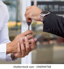 A businessman in a black suit  handling car key to the valet service staff. Close up