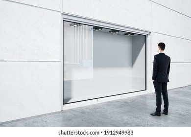 Businessman In Black Suit Looking At Empty Street Shop Window In Light Building Outside. Mockup