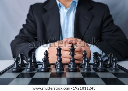 Businessman in black suit sitting and control team in front to success position on competition business game, meaning of success planning and strategy decision and achievement goal concept.