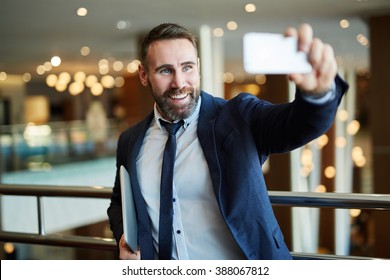 Businessman In Black Suit Using A Mobile Phone For A Video Call With Partners