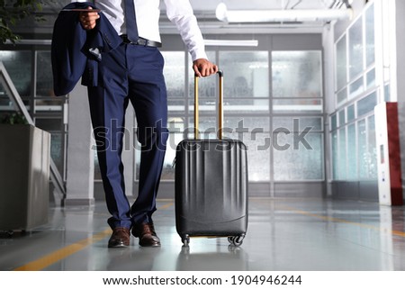 Businessman with black travel suitcase in airport. Space for text