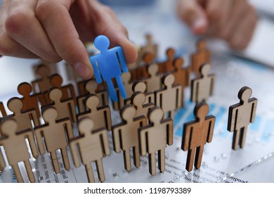 A Businessman In Blue Shirt Is Holding Object In His Hand, Is Searching For Personnel Or People. Detective Looking For Missing Person Crowd Of Miniature Figures Choosing Most Suitable One