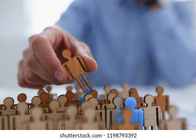 A Businessman In Blue Shirt Is Holding Object In His Hand, Is Searching For Personnel Or People. Detective Looking For Missing Person Crowd Of Miniature Figures Choosing Most Suitable One