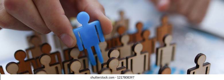 A Businessman In Blue Shirt Is Holding Object In His Hand, Is Searching For Personnel Or People. Detective Looking For Missing Person Crowd Of Miniature Figures Choosing Most Suitable One