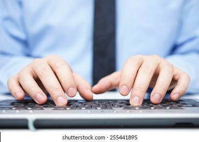 Businessman in blue shirt typing on computer keyboard