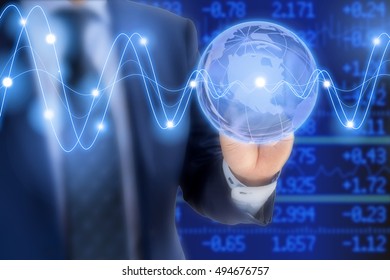 Businessman In A Blue Suit Tapping On A Glass Globe In Front Of A Stock Ticker Wall With Glowing Waves Global Business Concept