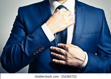 Бизнесмен в синем костюме завязывает галстук